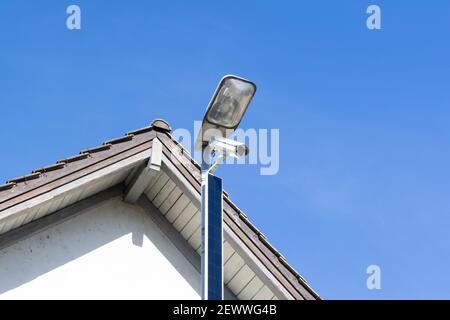 telecamera di sorveglianza a energia solare bianca di fronte alla facciata di una casa, la sorveglianza costante è un problema crescente nella nostra società, di giorno, senza persone Foto Stock