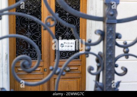 porta a graticcio in primo piano, porta di legno marrone sullo sfondo con testo tedesco, traduzione in tedesco: attenzione al cane, entrare a proprio rischio Foto Stock