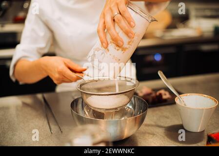 Chef femminile che usa il filtro mentre prepara la salsa al ristorante Foto Stock