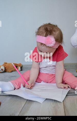 ritratto di bambina in tshirt rosa pittura mentre si siede su moquette Foto Stock