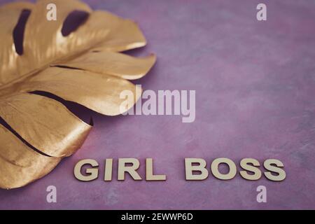 Pari opportunità Girl Boss testo in cima alla foglia d'oro simbolo di ricchezza e lusso su sfondo rosa Foto Stock