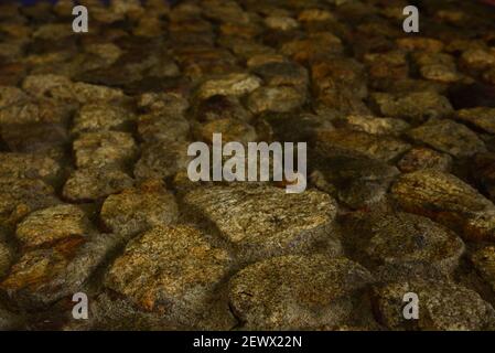 Un primo piano di un'antica roccia scura e sabbia sfondo parete Foto Stock
