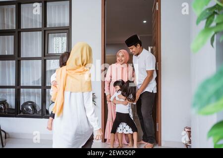 eccitata famiglia musulmana asiatica in visita amico durante eid fitri mubarak a casa Foto Stock