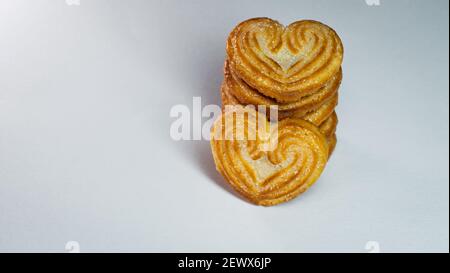 Primo piano di un piccolo biscotto a forma di cuore posto di fronte a una pila verticale. Foto Stock