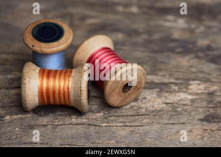 Tre fili da cucire su una superficie di legno di colore rosso, blu e arancione Foto Stock