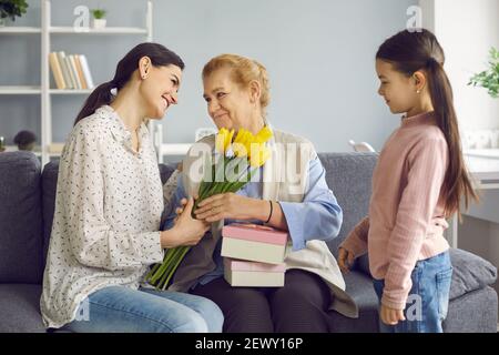 La donna anziana felice riceve doni in onore della Festa della Madre o della Giornata Internazionale della Donna. Foto Stock