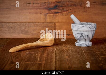 Cucchiaio di legno e mortaio e macinacaffè per pietre di marmo Frantoio su Old Barn legno pavimento e muro sfondo Shooting Sfondo del tavolo di superficie per M Foto Stock