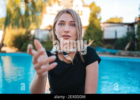 Il ritratto di una donna elegante appare stellato e si stende la mano. Sullo sfondo c'è una piscina e una casa. Concetto di emozioni umane ed e. Foto Stock