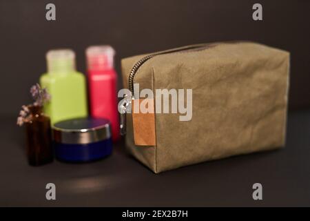 Borsa cosmetica da viaggio in carta ecologica riutilizzabile con kit di contenitori in plastica per il trasporto di shampoo, creme e cosmetici in viaggio su sfondo nero Foto Stock