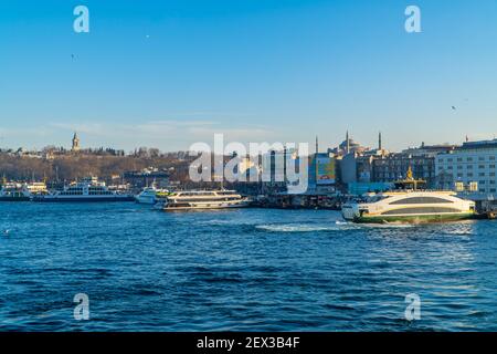 Istanbul, Turchia - 2 febbraio 2021 - splendida vista al tramonto dei moli di Eminönü con i traghetti e la Grande Moschea di Santa Sofia sulla collina Foto Stock