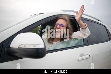 Donna che guida molto arrabbiato attaccando il suo braccio fuori dalla finestra in un ingorgo di traffico. Concetto di guida aggressiva. Foto Stock