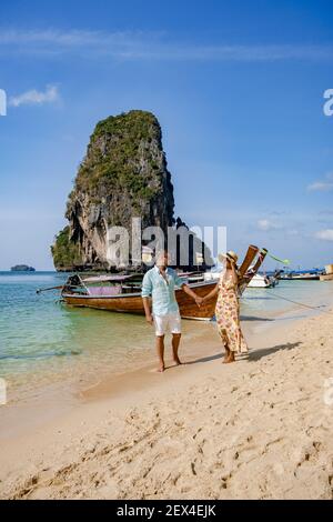 Coppia di mezza età su una spiaggia tropicale in Thailandia, turistica su una spiaggia tropicale bianca, Railay spiaggia con sullo sfondo barca a coda lunga. Railay Beach nella provincia di Krabi. Ao Nang, Thailandia. Foto Stock