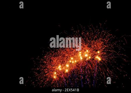 Immagine con sfondo nero preparata per modificare il testo di un fuochi d'artificio, formato da una moltitudine di piccoli punti di luce rossa con molti più grandi in oran Foto Stock