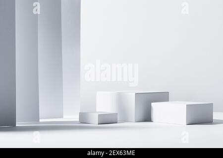 Design astratto minimalista per la presentazione e l'esposizione dei prodotti - podi quadrati bianchi alla luce del sole con ombre in interni geometrici bianchi. Foto Stock