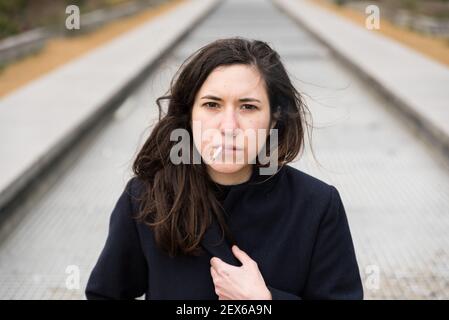 Ritratto esterno di una donna bianca di 28 anni con capelli castani, fumo Foto Stock