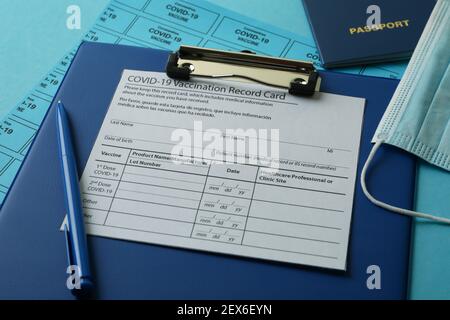 Covid - 19 concetto di vaccinazione con scheda di registrazione, maschera e passaporto su sfondo blu Foto Stock