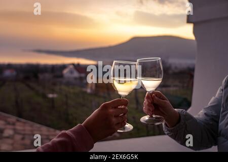 Brindate con bicchieri di vino al lago Balaton con il Badacsony collina sullo sfondo Foto Stock