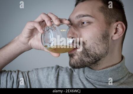 Ritratto di un giovane con una barba corta che beve un bicchiere di birra Foto Stock