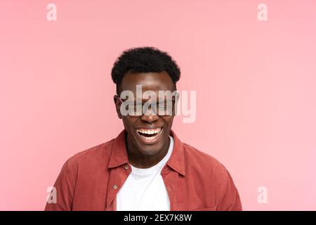 Ridendo positivo giovane afroamericano in camicia rossa di buon umore con occhi chiusi, isolato. Foto Stock