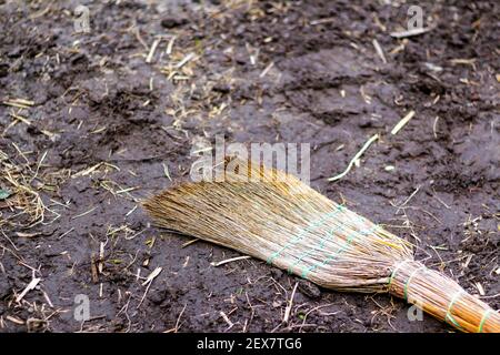 Defocalizzare scopa gialla sulla strada pulizia primaverile del giardino e orto UNA scopa si trova sul terreno e macinato con fieno ed erba asciutta su un Foto Stock