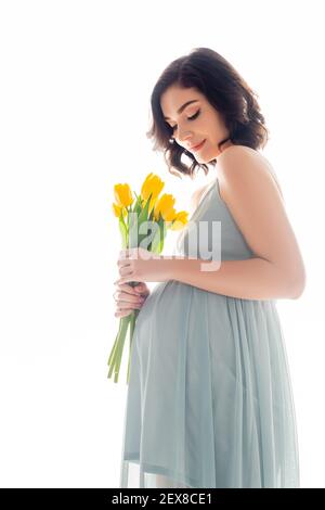 Bella donna incinta in abito che tiene tulipani isolato su bianco Foto Stock