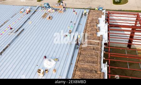 Addetti alla costruzione che installano pannelli isolanti e di tetto su un grande edificio di magazzino. Foto Stock