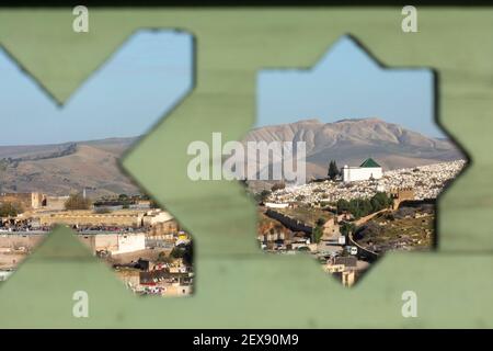 Vista dal paesaggio urbano del cimitero di Bab al-Futuh attraverso aperture decorative a forma di stella su una recinzione sulla terrazza del Palais Faraj, Fes, Marocco Foto Stock