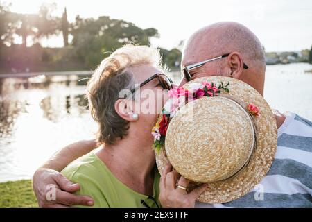 coppia di 60 anni che baciano in un parco Foto Stock