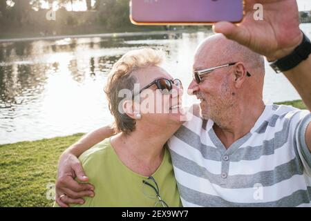 Coppia ritirata che prende un selfie in un parco Foto Stock