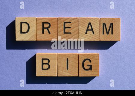 Dream Big, parole in lettere alfabetiche in legno isolate su sfondo viola Foto Stock