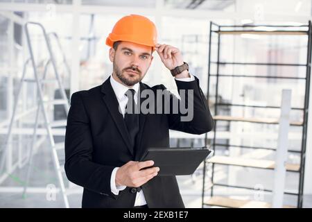 Uomo messo a fuoco in tuta e cappello usando il tablet al lavoro Foto Stock