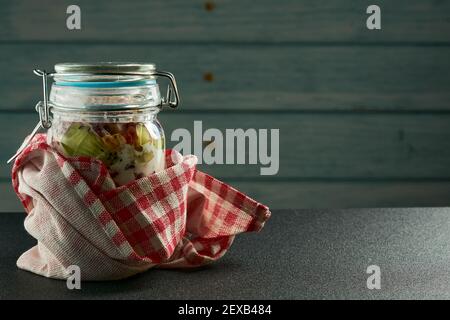 Vasetto di yogurt fresco con frutta e bacche al suo interno su sfondo di legno blu. Foto Stock
