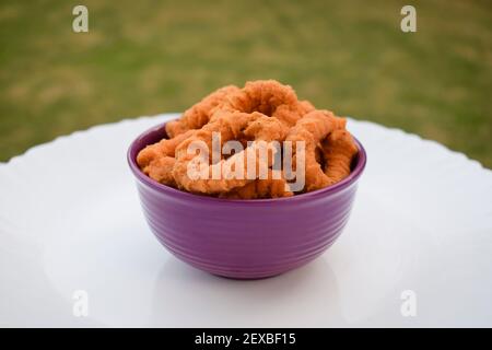 Vista laterale del tipico snack indiano del sud, tè serale, Chegodilu o murukku anello isolato su sfondo bianco in piatto bianco servito d Foto Stock