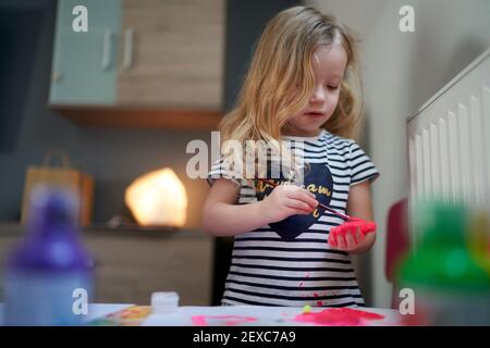 Carino bambina essendo creativa con vernice sui suoi palmi. Foto Stock