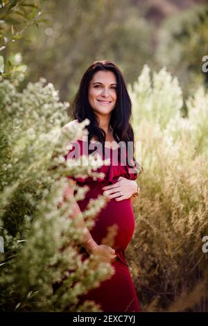 Wantant Mother in piedi sul campo sorridendo per la macchina fotografica a San Diego Foto Stock