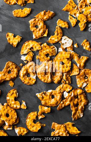 Disposizione flatlay di pretzel snacking sparsi su una superficie di grigio scuro. Foto Stock