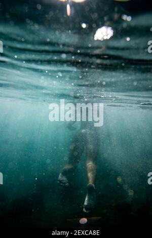 le donne nuotano e calci lontano dalla macchina fotografica nel caldo oceano Foto Stock