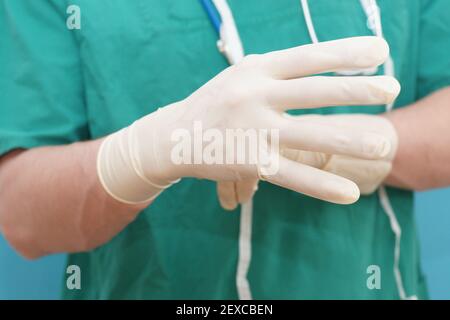 Il medico si prepara per l'intervento chirurgico e mette su guanti di gomma ospedale igiene Foto Stock