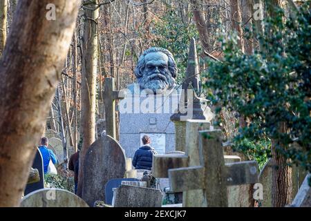 Turisti che visitano la tomba di Karl Marx nel cimitero di Highgate, visto dall'adiacente Waterlow Park, Londra, Regno Unito Foto Stock
