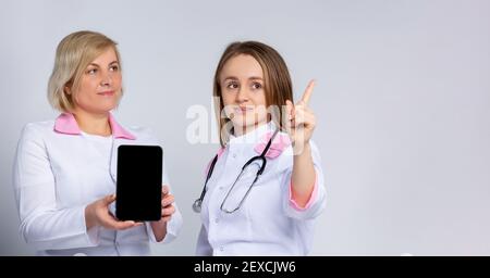 Banner - formato lungo. Indice su. I medici che utilizzano un computer tablet digitale simulano lo schermo nero, consultando il paziente online. Videochiamate in grigio Foto Stock
