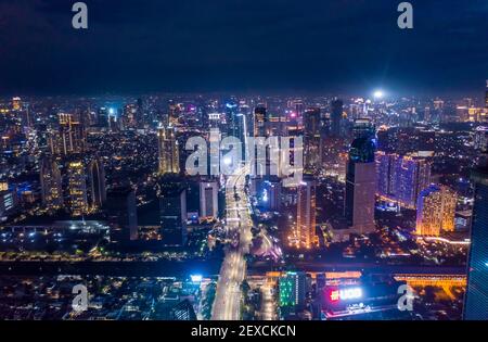 Paesaggio notturno aereo di grattacieli e traffico autostradale a più corsie nel moderno centro cittadino di Giacarta, Indonesia Centro cittadino urbano con alti edifici di notte Foto Stock