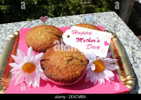 vassoi dorati con placemat rosa contenente 3 muffin per la mamma con biglietto d'auguri e decorazioni Foto Stock