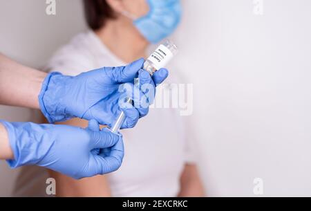 Le mani si sono gulozate, aspirando il vaccino covid-19 in una siringa da un flaconcino. Vaccinazione di una donna anziana, primo piano, copia spazio. Foto Stock