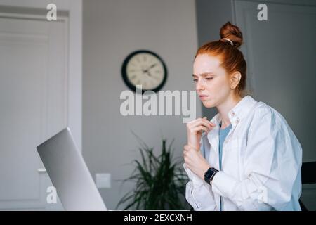 Giovane donna d'affari che soffre di testa rossa che ha dolore al polso durante il lavoro sul computer portatile Foto Stock