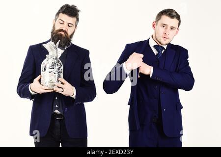 Uomini in tuta, uomini d'affari con vaso pieno di contanti, banconote di carta, sfondo bianco. L'uomo in stile oldfashioned preferisce i contanti, il ragazzo moderno mette la mano in tasca dove tiene la carta. Concetto di sicurezza per il risparmio. Foto Stock