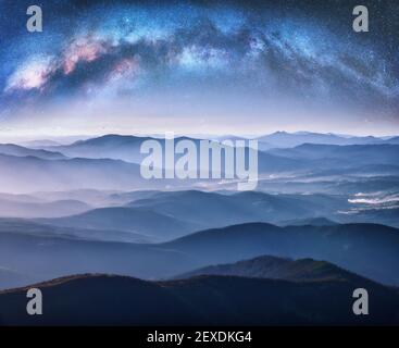 La Via Lattea si inarca sulle montagne in nebbia a stellata notte Foto Stock