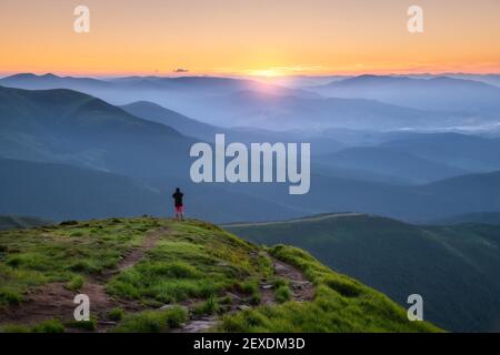 Uomo sportivo sulla cima della montagna che guarda sulla valle di montagna Foto Stock