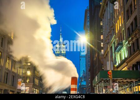 L'Empire state Building si illumina tra gli edifici del centro di Manhattan durante le festività natalizie a New York City. Foto Stock