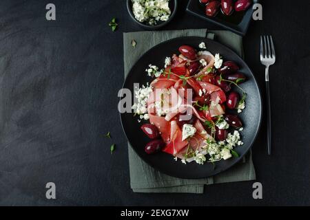 Antipasti su piatto scuro con jamon, olive e formaggio blu. Vista dall'alto. Foto Stock