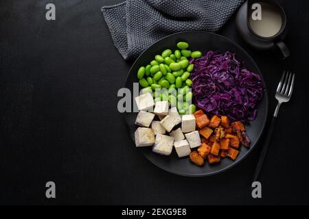 Gustosa e appetitosa ciotola vegana con tofu sul piatto. Vista dall'alto Foto Stock